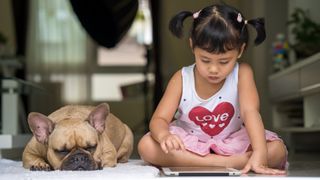 Dog and girl sat down looking at an iPad