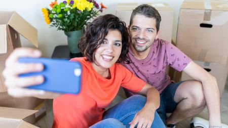 Happy couple taking a selfie in new home
