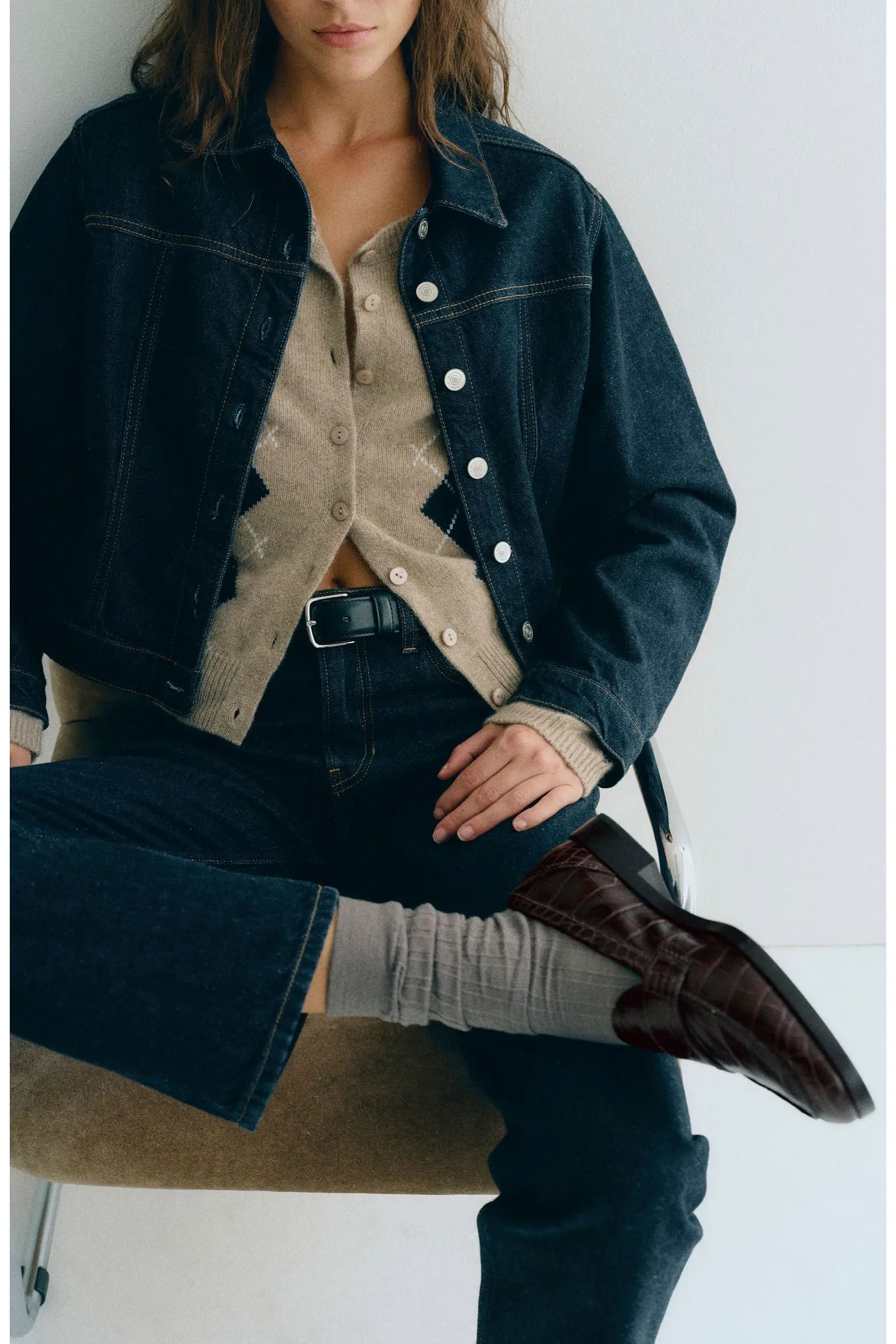 A Reformation model sitting in a chair wearing socks and loafers