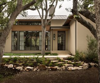 Modern house with large glass doors, garden pathway with oak trees