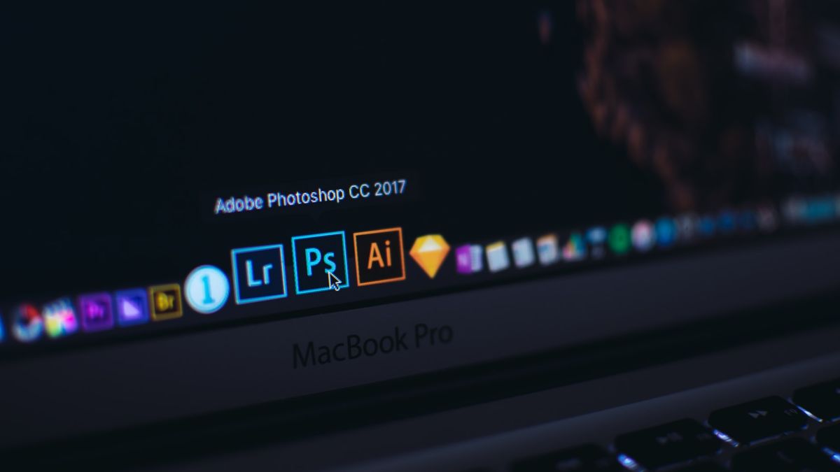 Adobe Creative Cloud discount - MacBook taskbar with Adobe CC product icons shown