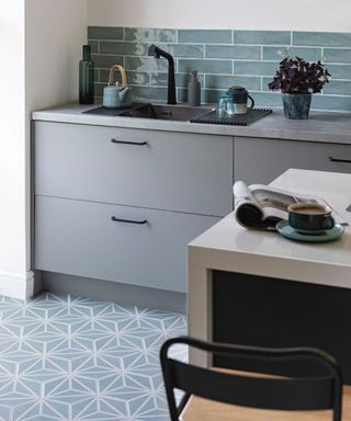 Playful kitchen scheme with patterned floor and wall tiles in soft, tonal blues