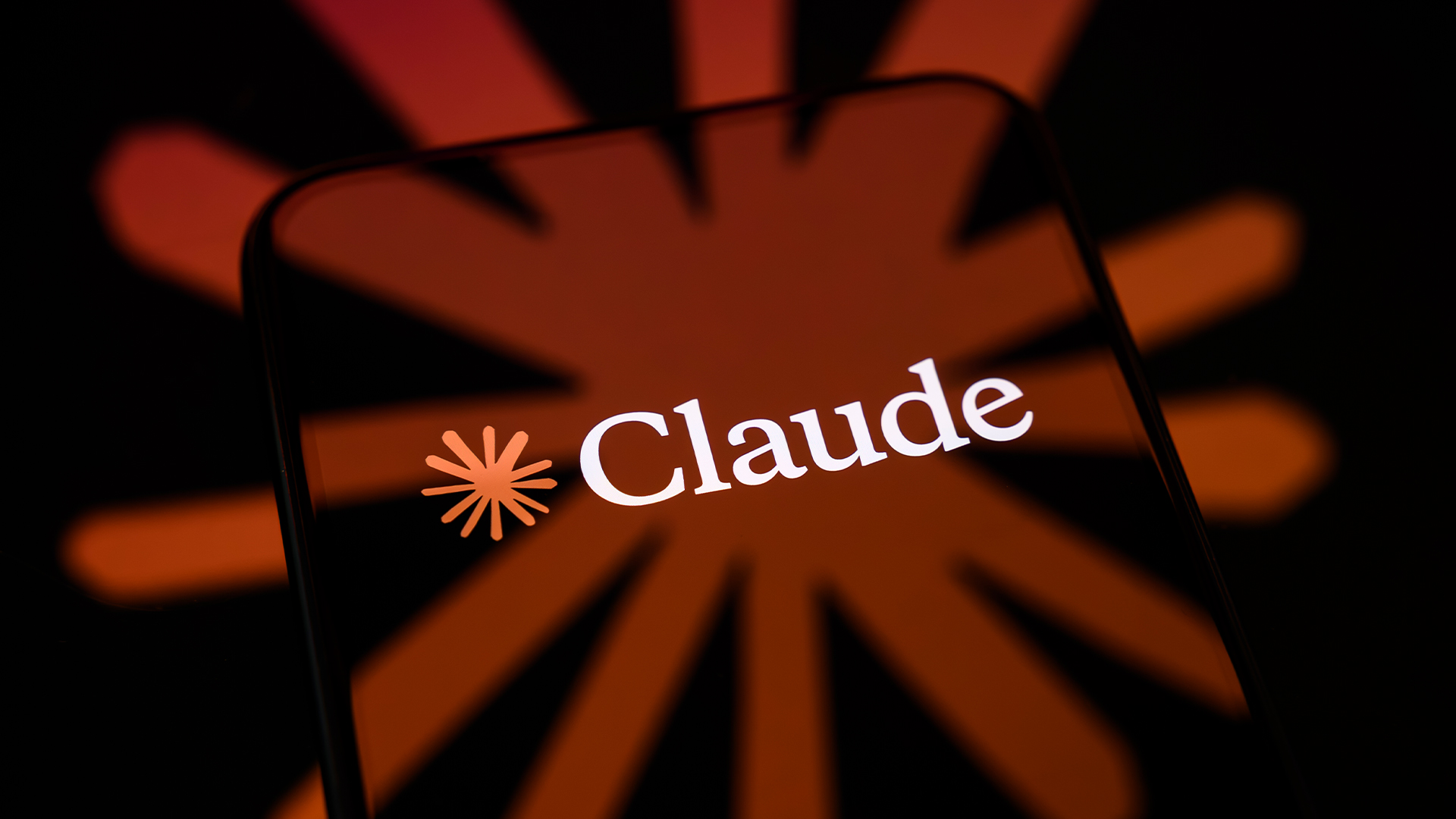 Logo and branding of Anthropic's Claude AI tool pictured on a smartphone screen, with branding blending into background.