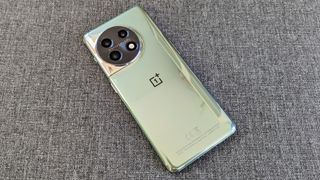 OnePlus 11 phone, reflective green finish, laid on grey surface