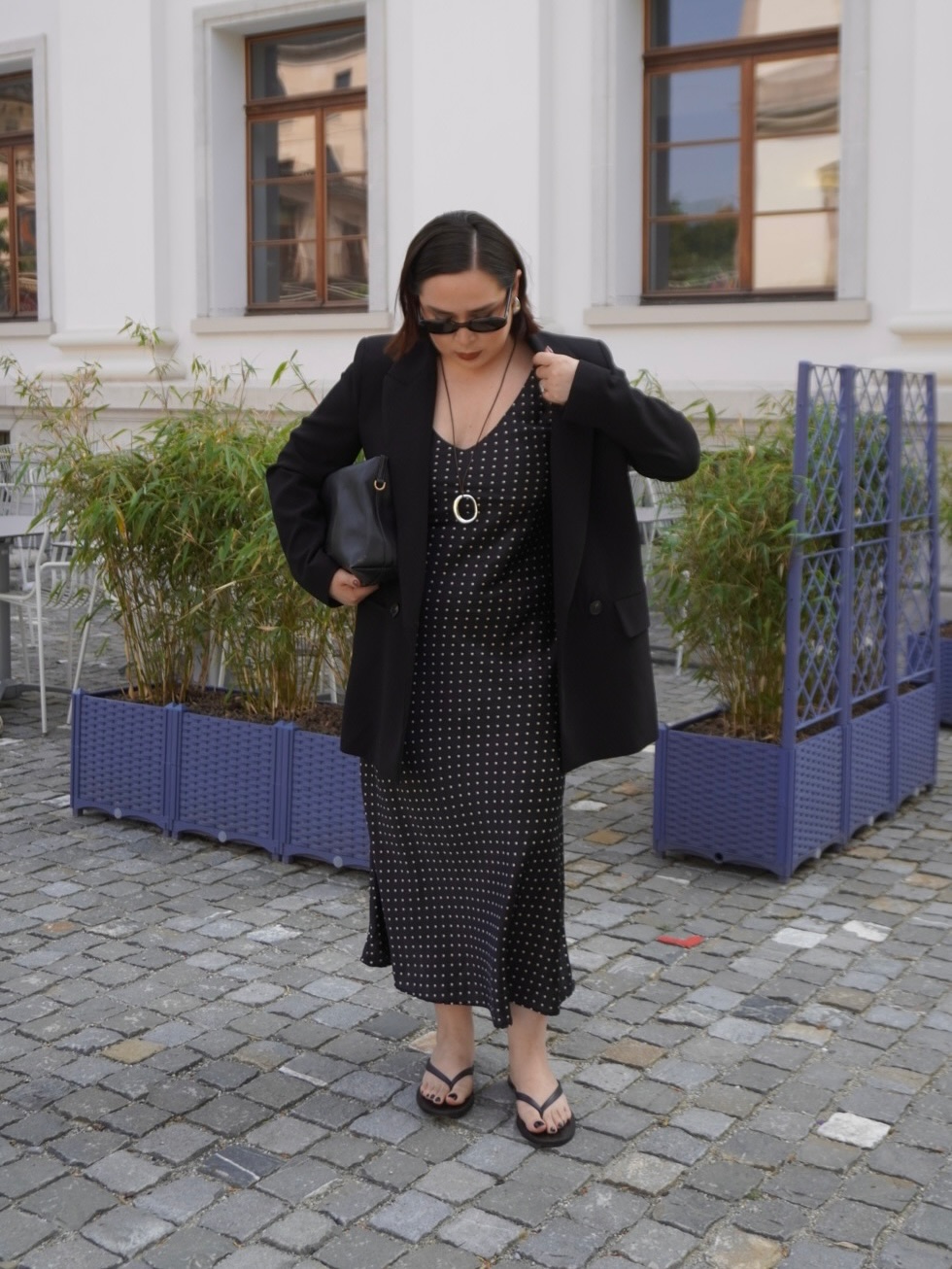 @indiraci wears a black polka dot dress with a blazer and flip-flops