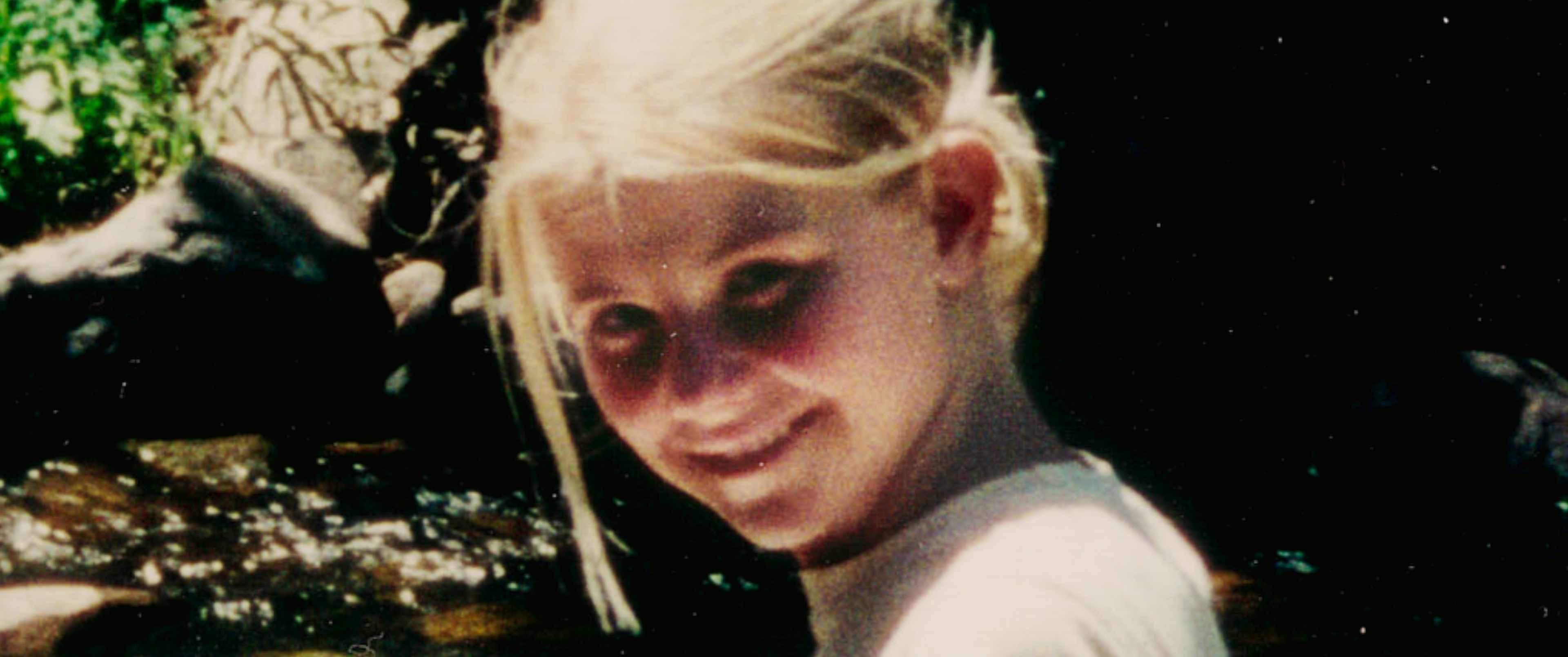 Elizabeth Smart as a child smiling at the camera by a creek in a still of an old photo featured in the netflix documentary kidnapped