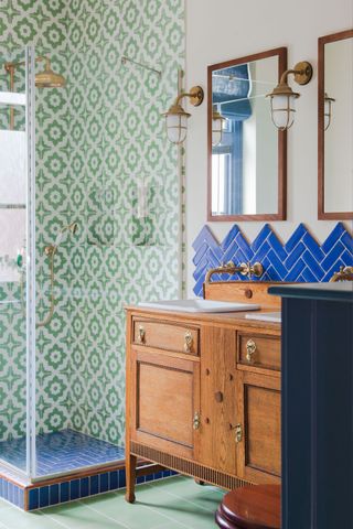 bright green tiles in shower with bright blue tiles over vintage vanity unit and brass lantern fittings