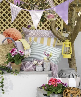 A cozy garden corver with bunting and plenty of inviting cushions and throws