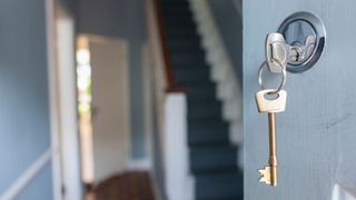 pair of keys in the front door of a house, door is blue