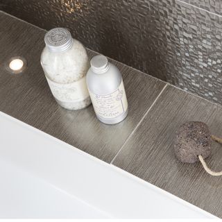 closeup of brown metallic tiled ledge spotlights pumice stone spa bath products