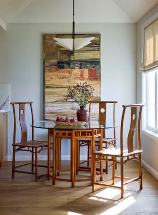 Wall painted in Benjamin Moore Gray Owl behind glass and wood dining table.