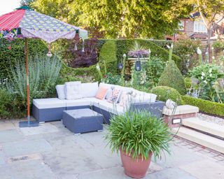 A corner sofa in a small garden with evergreen structure