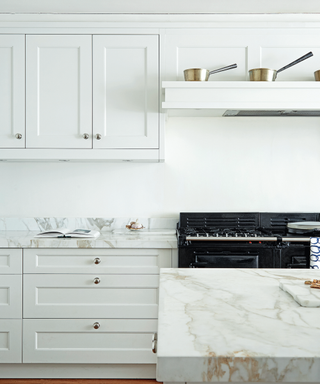 A white kitchen color scheme with marble countertops and a black oven.