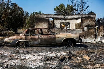 A car and house destroyed by the Clayton Fire.
