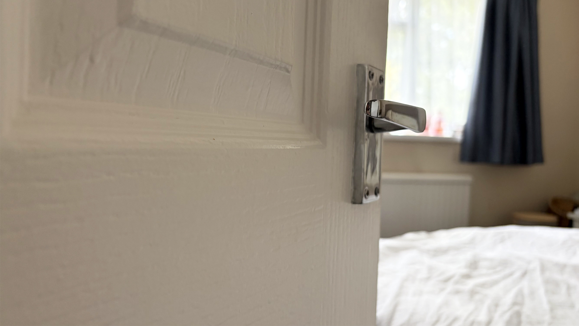 A close up of a door handle and an open door leading to the bedroom of sleep writer Ruth Jones