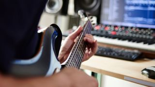 A man plays electric guitar in a recording studio
