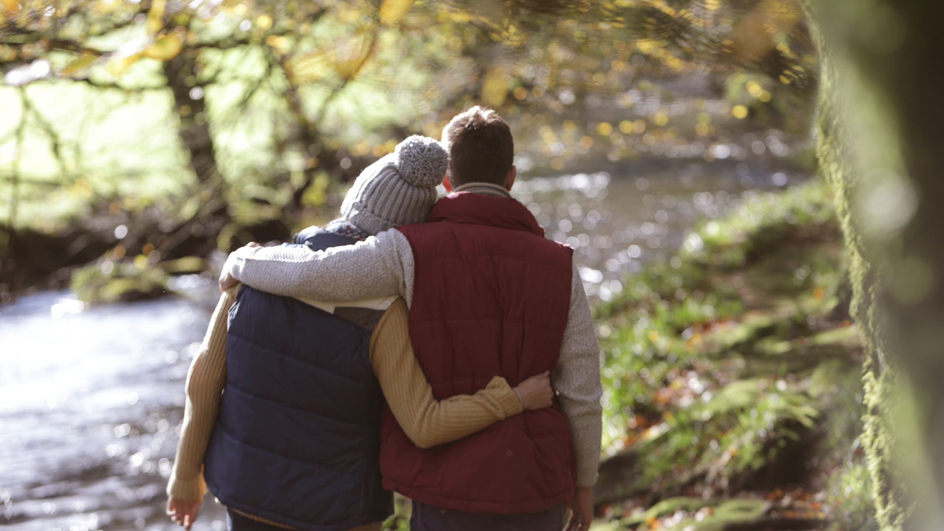 Couple walking in woodland next to river