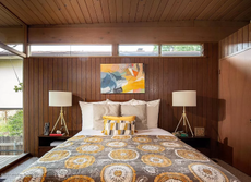 A cabin-style bedroom with wood panelled walls