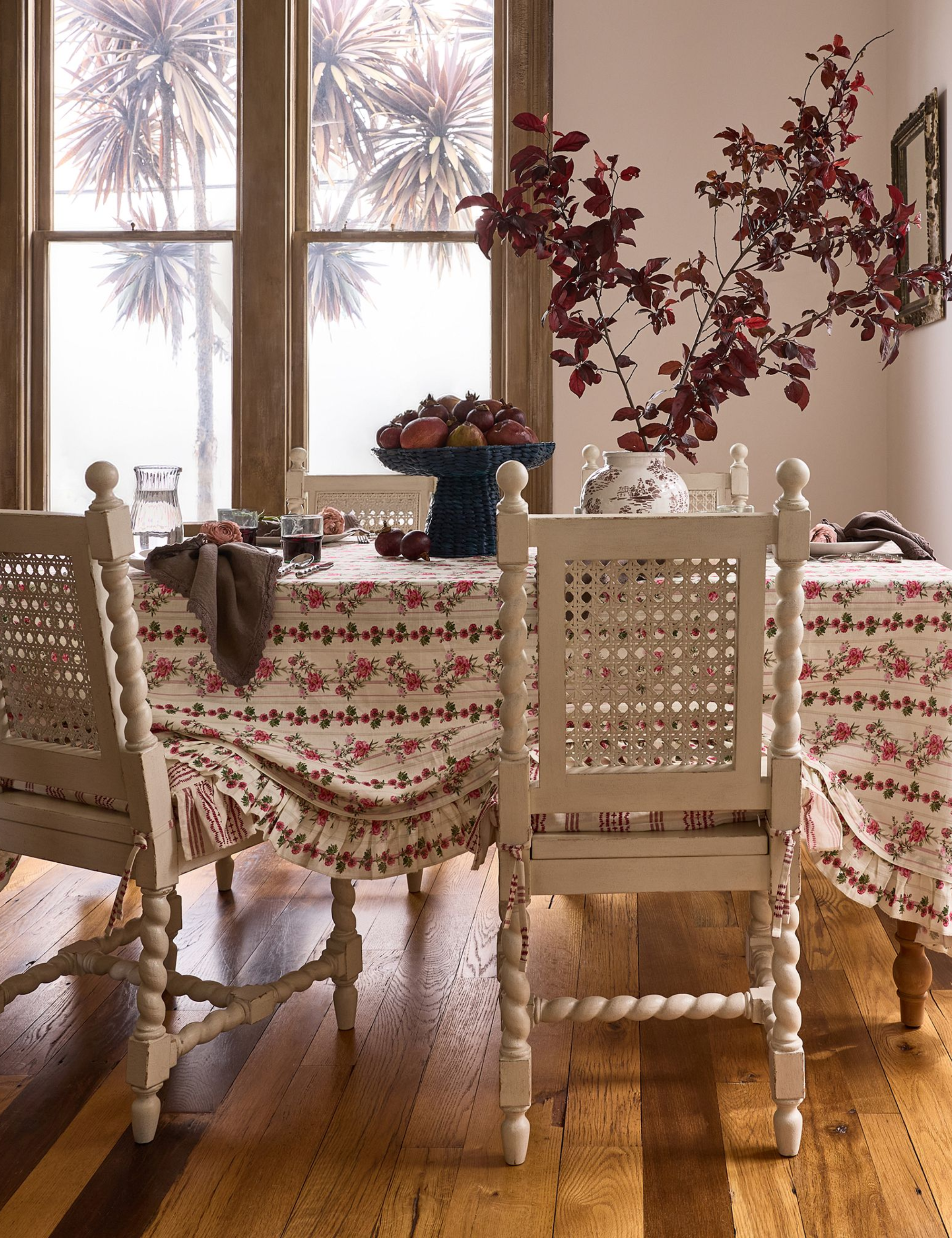 A folkloric fall table featuring heritage-inspired table linens, a pedestal bowl of fruit, and an oversized oxblood leaf centerpiece.