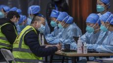 Chinese workers wait to receive a COVID-19 vaccine jab