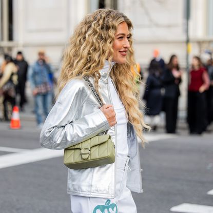Best hair products for frizz - Emili Sindlev wears silver jacket, pants with NY print, turtleneck, green bag - gettyimages 2007516071