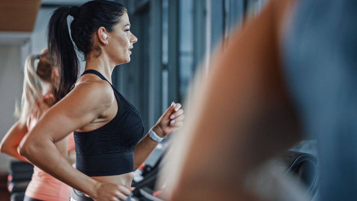 Woman running on treadmill wearing earbuds