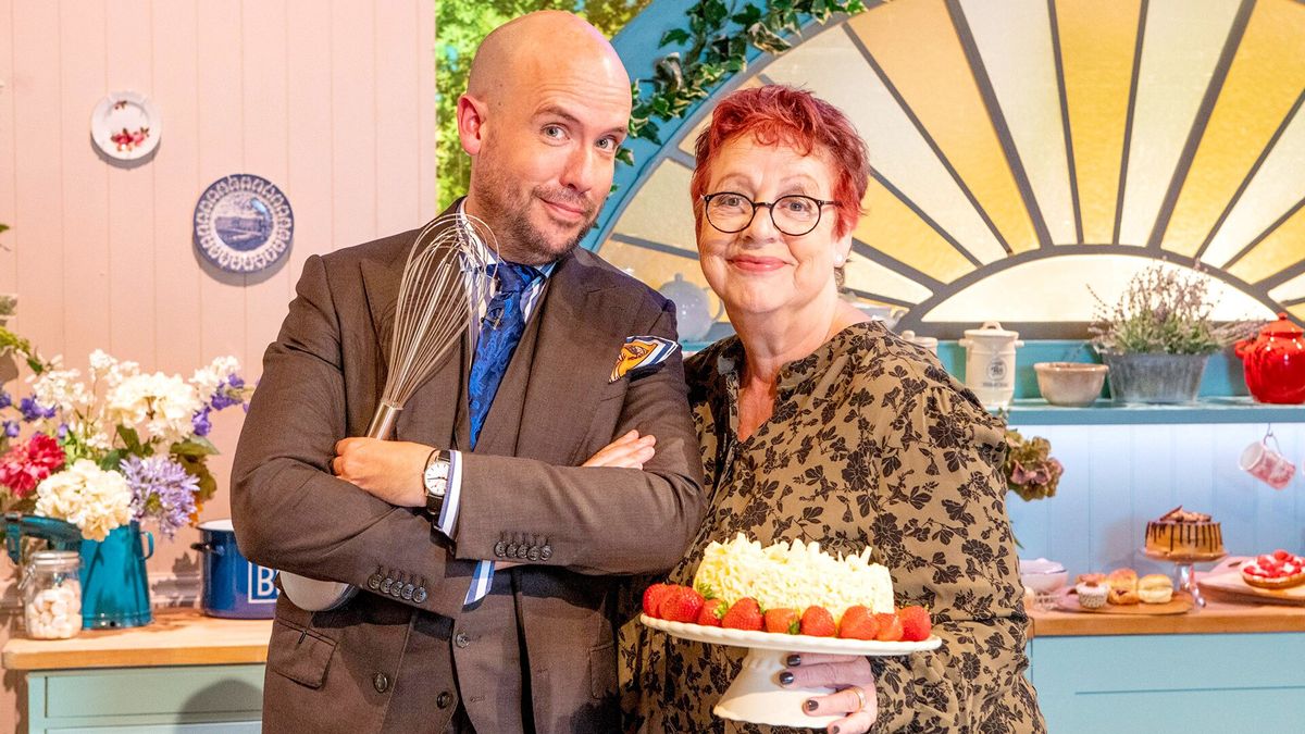 The Great British Bake Off: An Extra Slice hosts Tom Allen and Jo Brand posing with a whisk and a cake