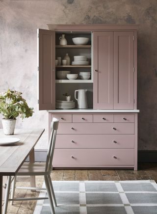 A pink dresser with drawers and cupboards used as a pantry cupboard in a kitchen by Neptune