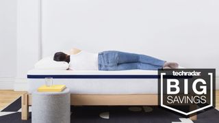 A woman with dark hair and wearing a white vest and blue jeans sleeps on her side on the Helix Sleep Midnight Mattress