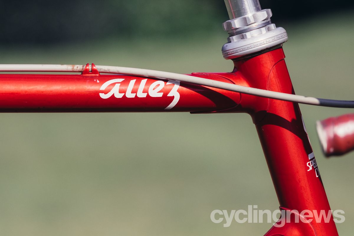 Close up of a red bikes top tube with a cursive Allez logo