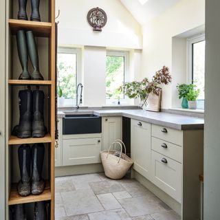 boot room with limestone flooring and pale painted cabinets