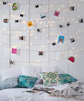 A set of polaroid photographs affixed to fairy lights in bedroom