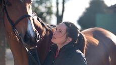 Young woman looking up her horse