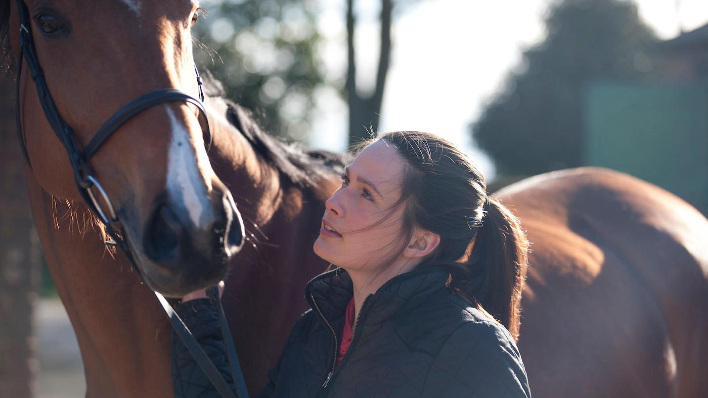 Young woman looking up her horse
