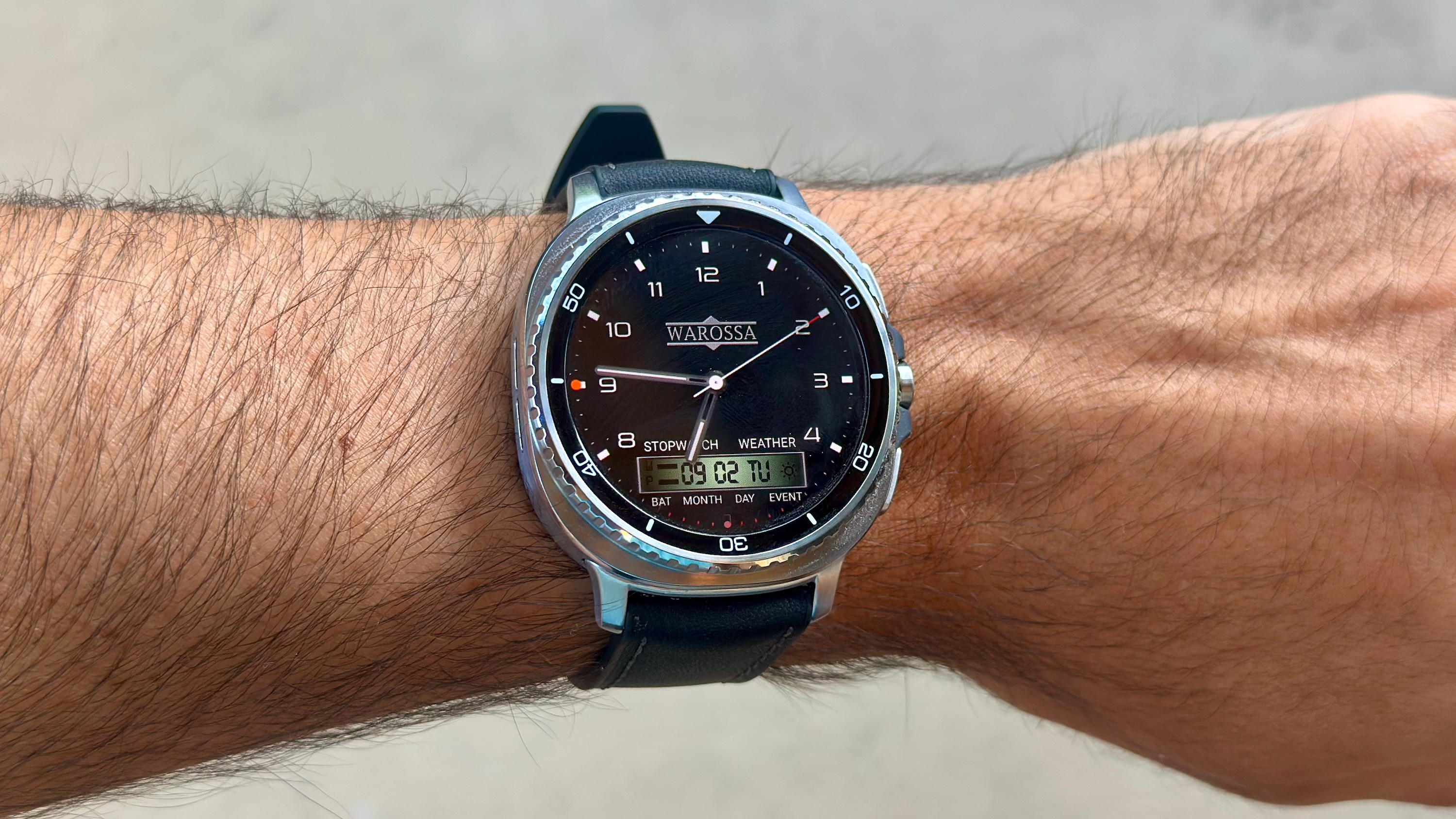 The Samsung Galaxy Watch 8 Classic on a person's wrist, showing a custom watch face from the WatchMaker app imitating a Warossa watch.
