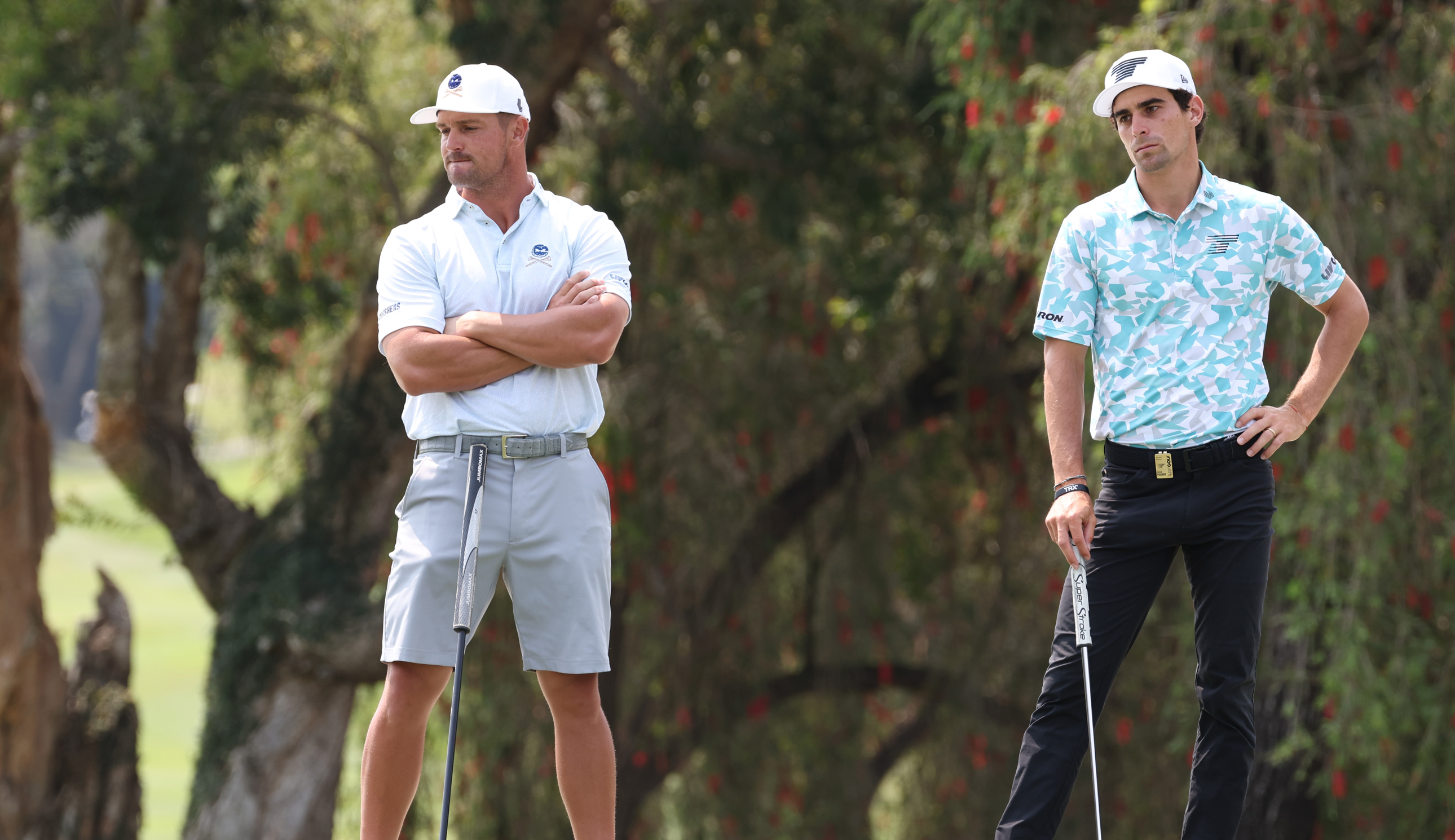 Bryson DeChambeau and Joaquin Niemann wait to putt