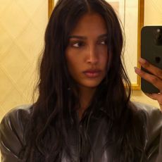 Jasmine Tookes taking a selfie in a mirror wearing a black leather jacket