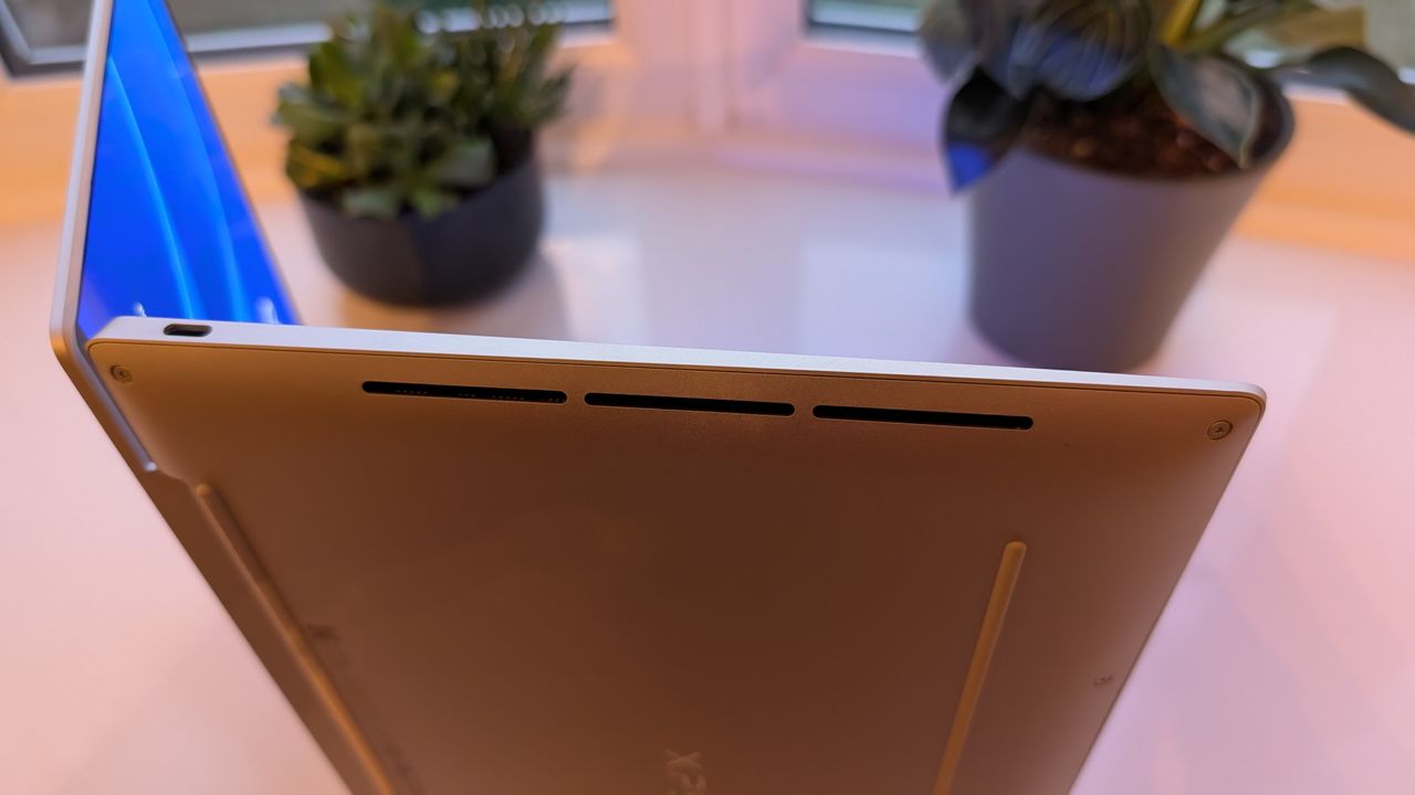 The Dell XPS 13 pictured on a white surface in front of a window with two potted plants.