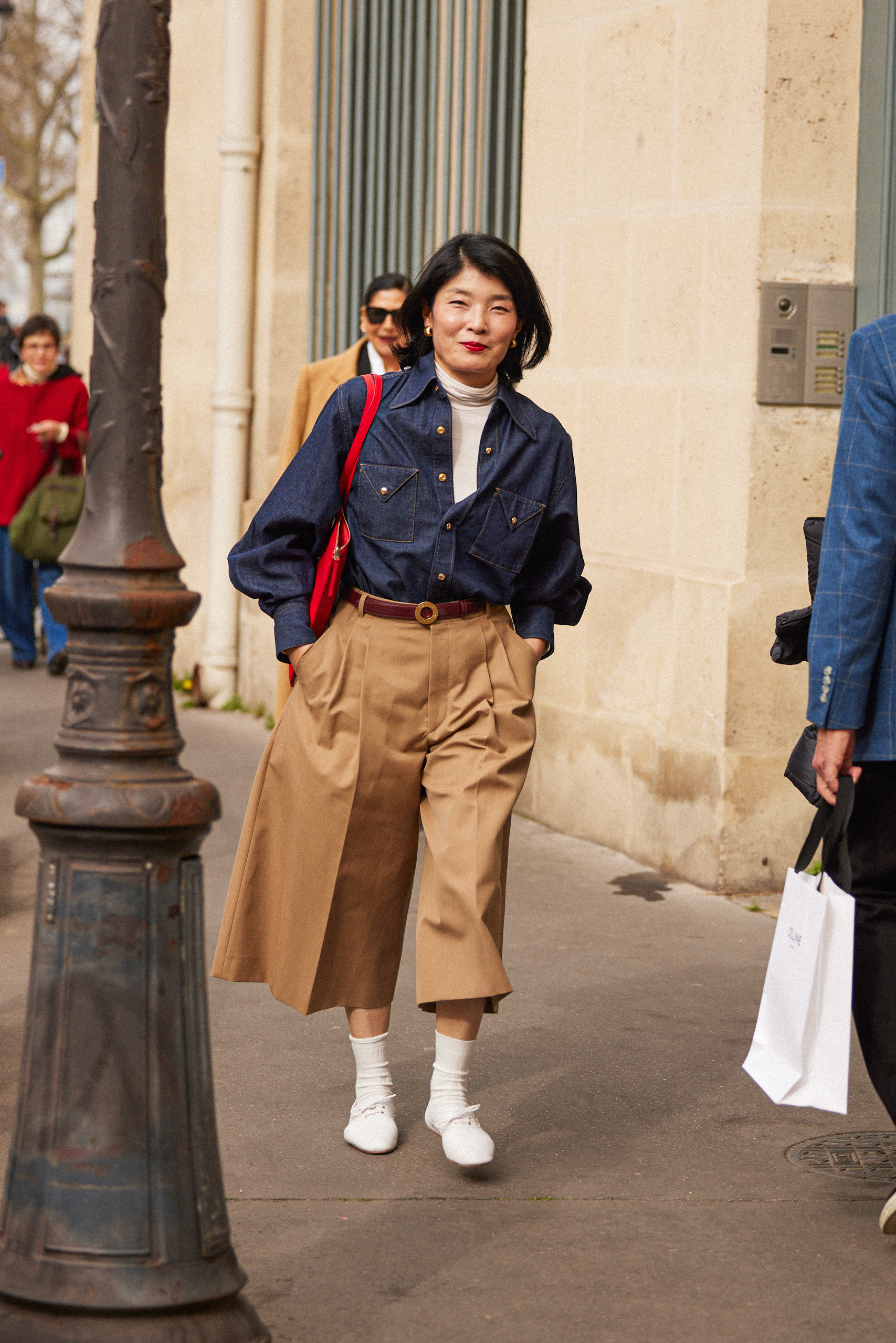 Paris fashion week showgoer wears long shorts with white Derby shoes and a denim shirt.