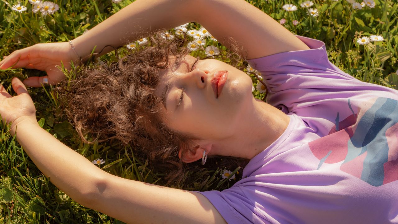 Best Retinol Body Lotions - Beautiful young lady enjoying the sun in the park - getty images - 1499992339