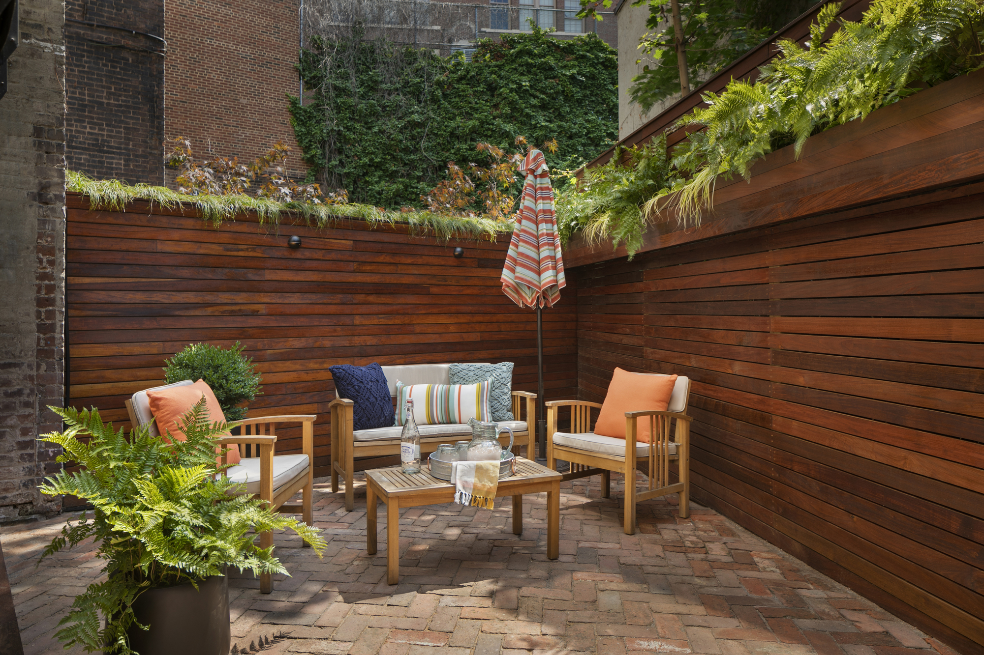 A backyard patio with a high fence and a garden furniture set