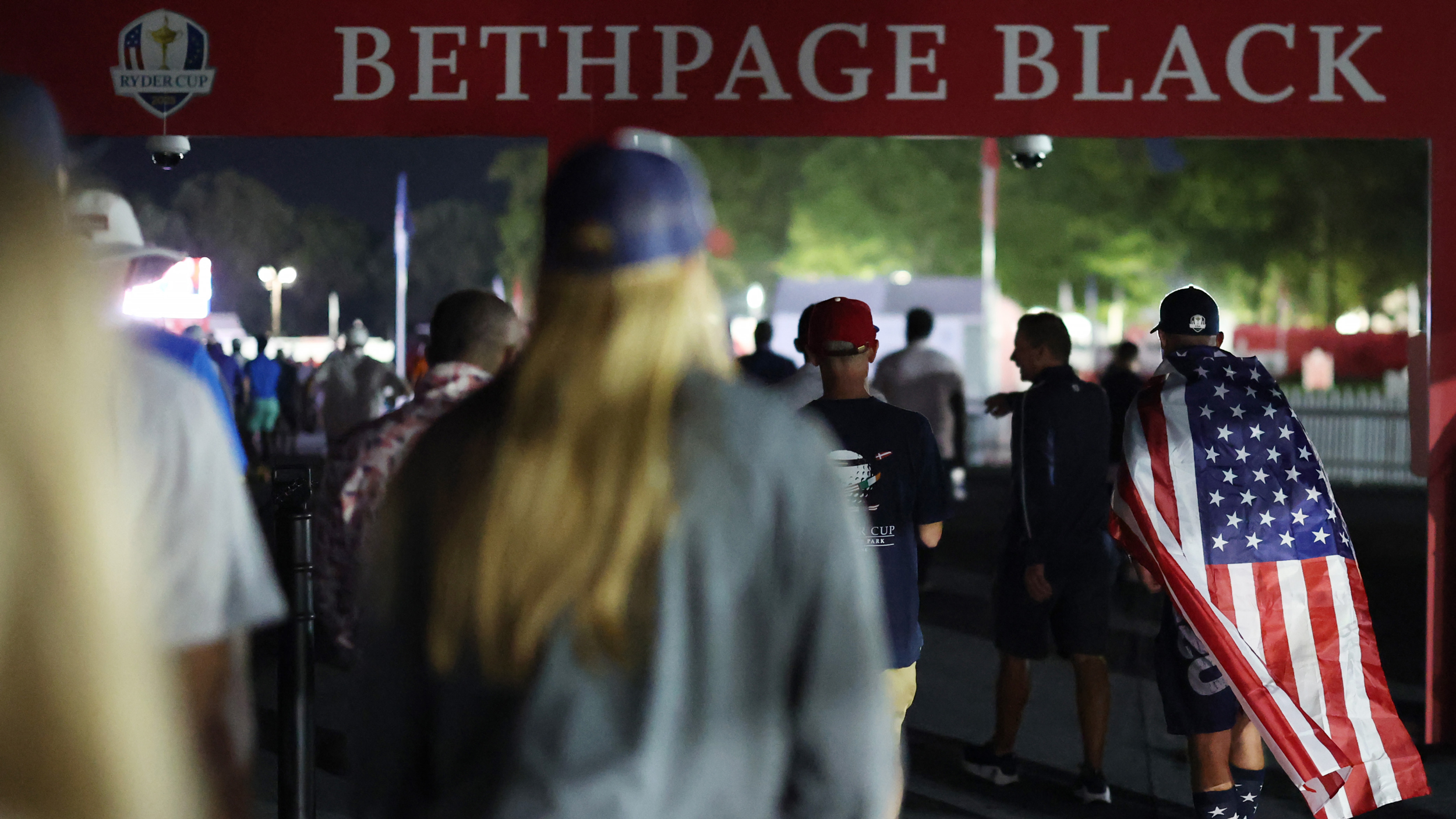 Fans enter the 2025 Ryder Cup at dawn and pass under a Bethpage Black sign
