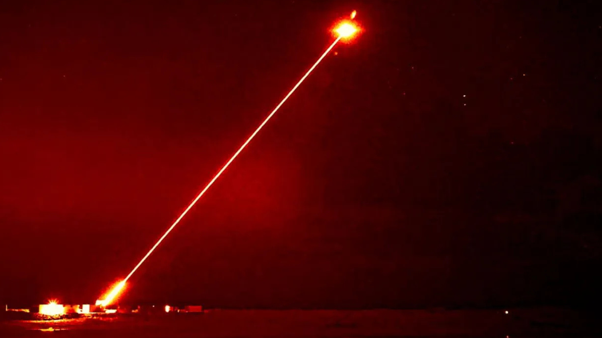 The DragonFire system firing a bright red laser, engaging a drone mid-air.