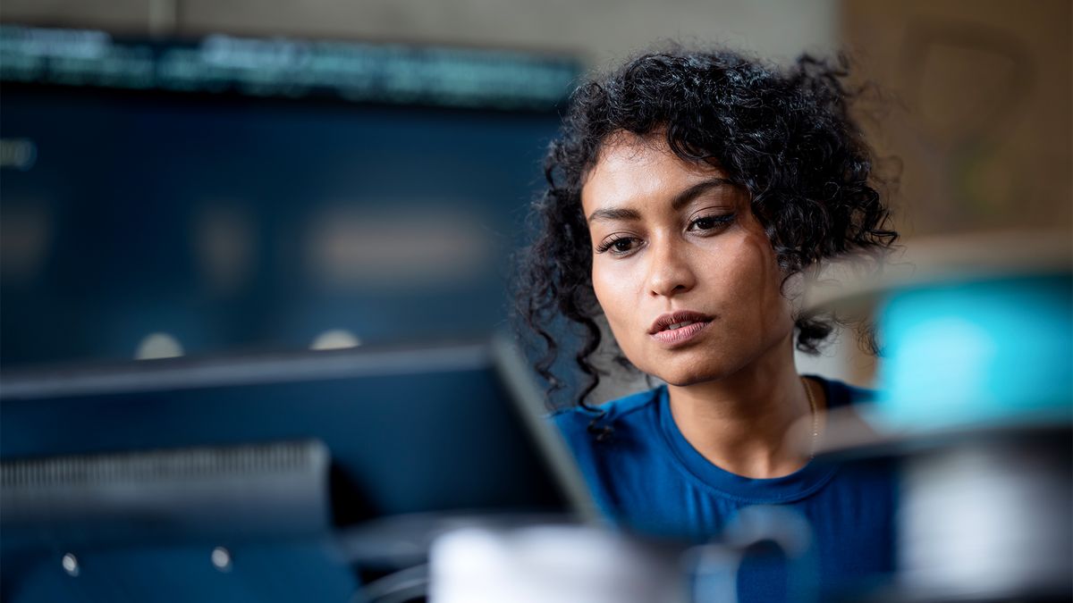 Female data privacy professional working on a desktop computer in an office space.