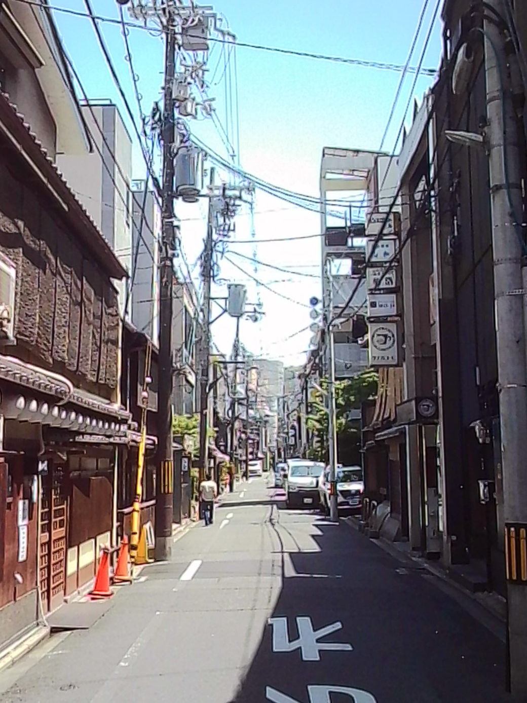 Narrow Japanese street with traditional buildings, overhead wires, and a small van.