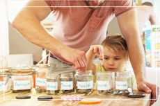 Young girl and father sorting money into jars