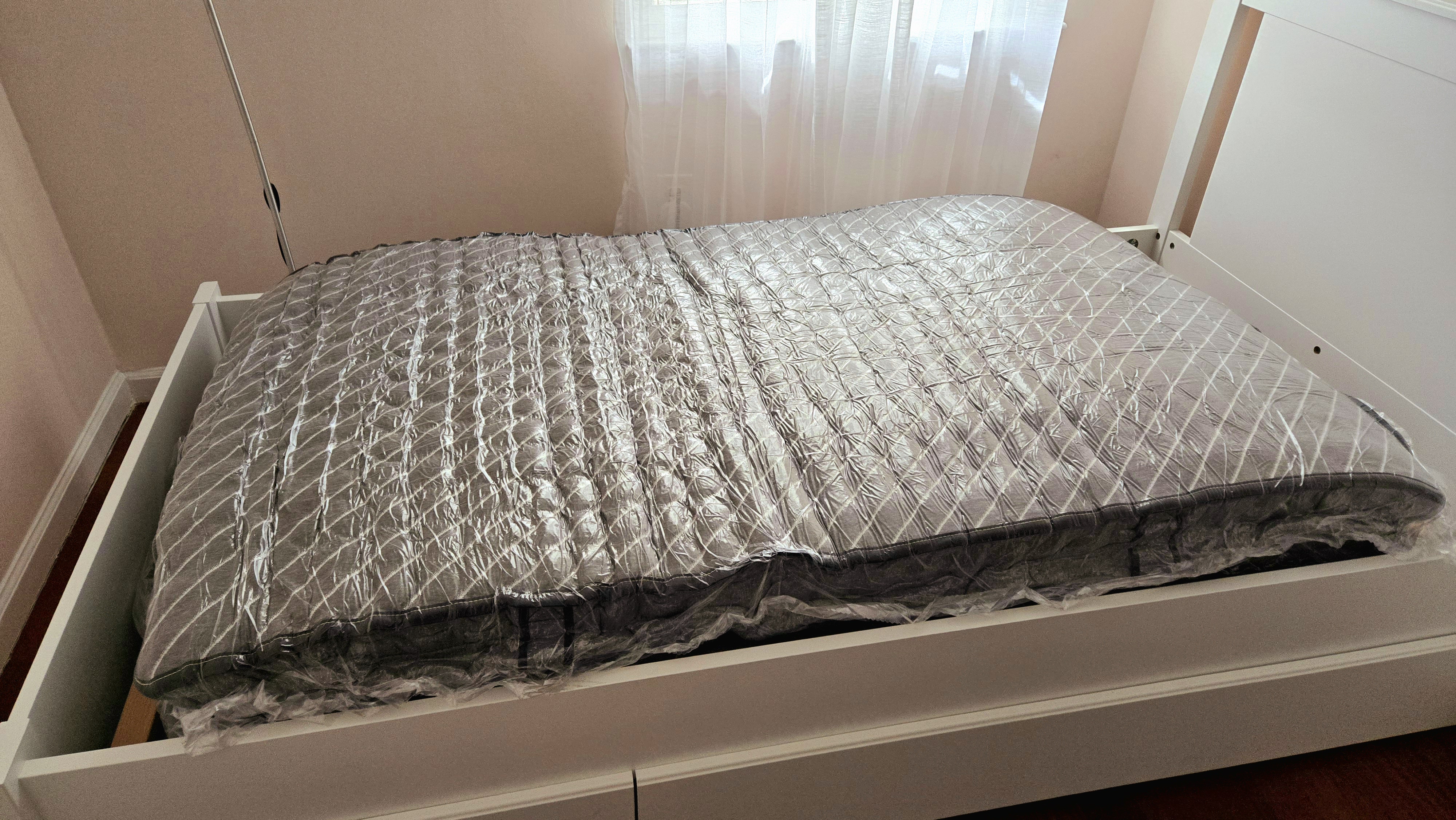 Siena Premier Hybrid Mattress wrapped in plastic on our tester's slatted bed during setup