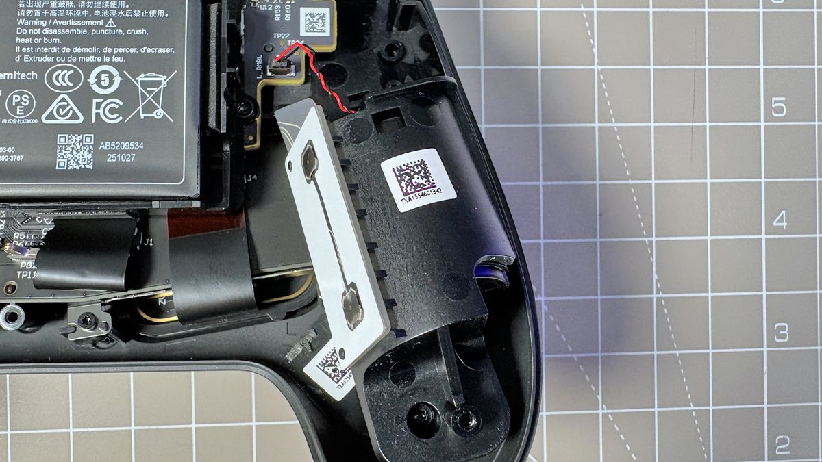 The Steam Controller on a desk during a teardown, with various parts removed.