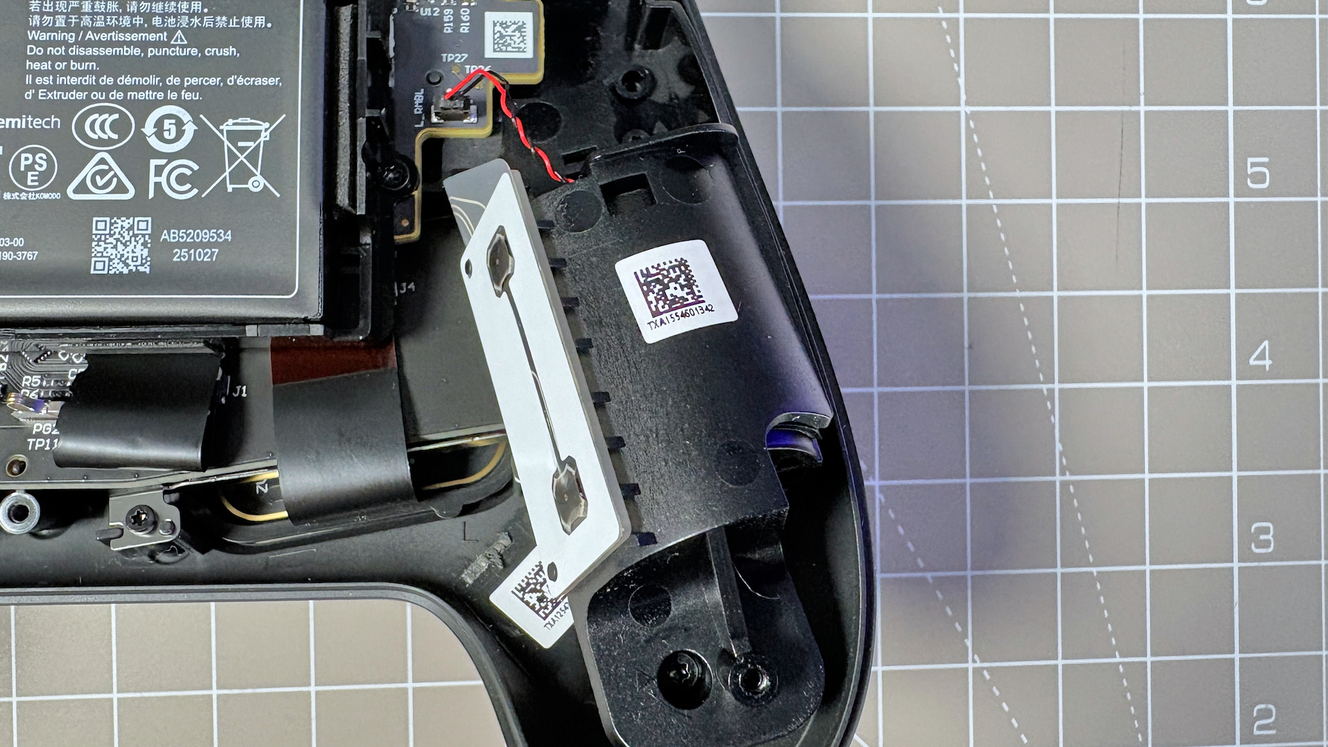 The Steam Controller on a desk during a teardown, with various parts removed.