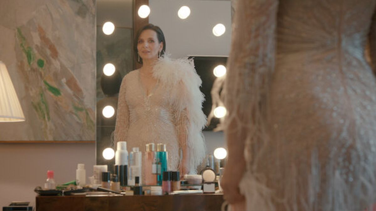 A woman stands looking at herself in a vanity mirror 